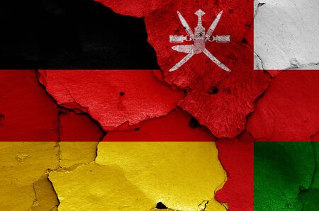 flags of Germany and Oman painted on cracked wallの写真素材