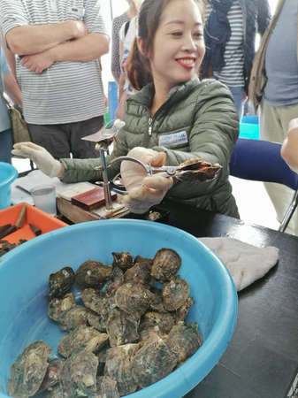 Ha Long, Vietnam - February 26, 2020: Vietnamese girl showing how they extract pearls from shellsのeditorial素材
