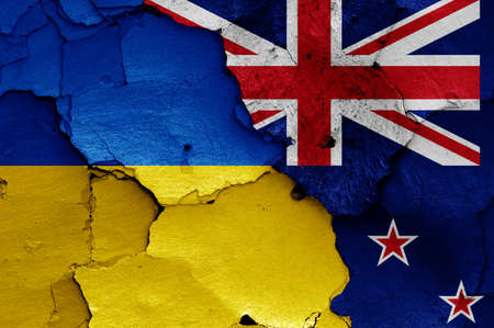 flags of Ukraine and New Zealand painted on cracked wallの写真素材