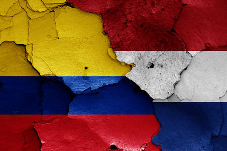 flags of Colombia and Netherlands painted on cracked wallの写真素材