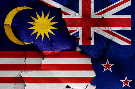 flags of Malaysia and New Zealand painted on cracked wallの写真素材