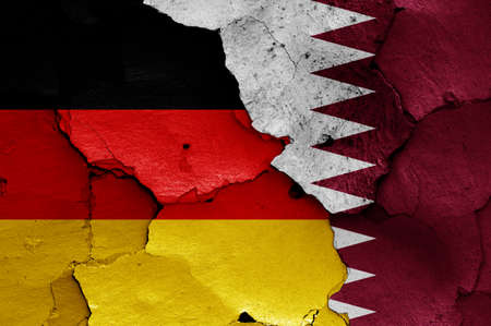 flags of Germany and Qatar painted on cracked wallの写真素材