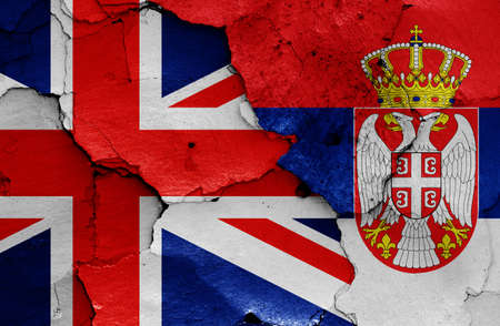 flags of UK and Serbia painted on cracked wallの写真素材