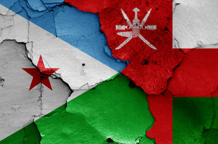 flags of Djibouti and Oman painted on cracked wallの写真素材