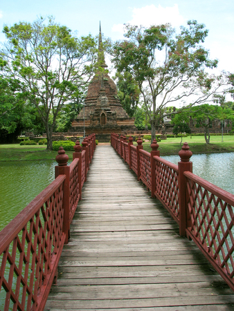 This is a red painted bridge that leads to an island temple in Sukhothai Thailand.の写真素材