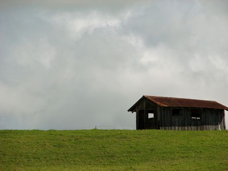 a single barn on a gren hillside.の写真素材