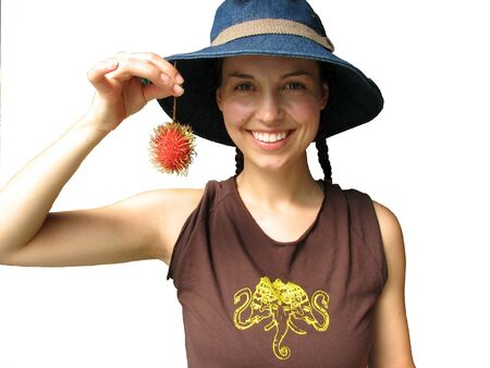 A young woman holding up the tropical fuit Rambutan.の写真素材