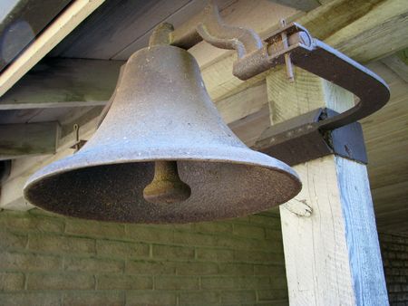 An old metal farm bell fixed to a post.