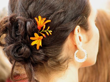 Yellow and orange flowers tucked in to the hair of a sunlite woman.の写真素材