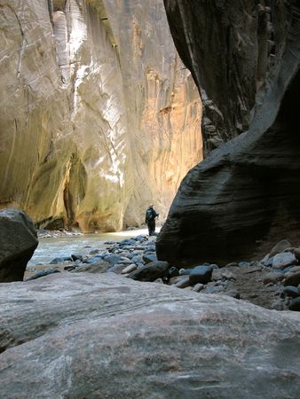 A hiker going around the corner in the Narrows of Zion Canyon.  Utah, U.S.A.の写真素材