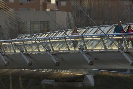 Pasarela del Voluntariado, Zaragoza, Spain - February 2, 2020: Some people cross the Ebro River carelessly across the Volunteer Bridge at sunset.のeditorial素材