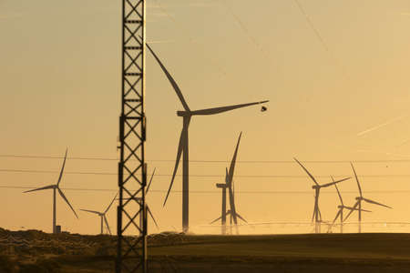 Silhouettes of wind turbines in operation, while agricultural irrigation systems work automatically...