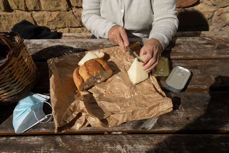 A senior woman, cuts slices of goat cheese at the mountain hut of the fountain of Artica, in Luesia,...