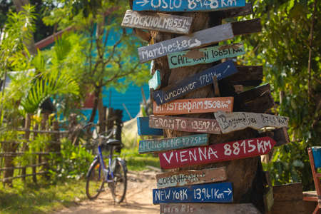 Colorful hand painted direction wood signs to different cities of the world, and mileage marker in Don Det island, one of the famous Four Thousand Islands or Si Phan Don, in the Mekong river, Laos.の写真素材