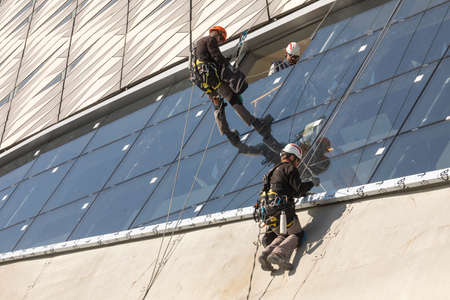 Zaragoza, Spain - Sep. 30, 2020: Specialist technical workers carry out maintenance and rehabilitation work, wearing safety harnesses, on the facade of the Zaragoza bridge pavilion.のeditorial素材