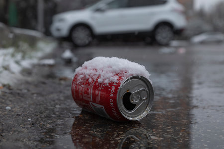 Madrid, Spain - January 07, 2021: A red Coca Cola can, covered with snow, thrown on the street, dirtying and polluting the urban environment.のeditorial素材