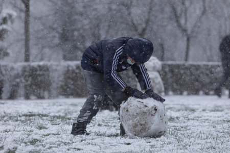 Madrid, Spain - January 07, 2021: Children playing with snow and making snowmen, in the Buen Retiro park in Madrid, in the middle of a snowy day, due to a wave of polar cold.のeditorial素材