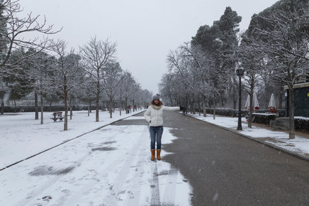 Madrid, Spain - January 07, 2021: A young girl enjoys a walk through the Buen Retiro park in Madrid, in the middle of a snowy day, due to a wave of polar cold.のeditorial素材