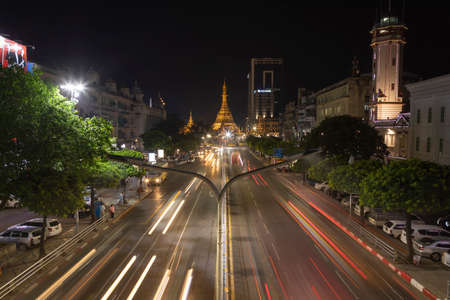 Yangon, Myanmar - December 19, 2019: Detail of night traffic towards Sule Pagoda Buddhist temple and stupa, from the Sule Paya Road Pedestrian Bridge, in long exposure photography.のeditorial素材