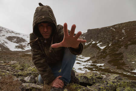 Stock photo of a man wearing camouflage clothing, and trekking in the high mountain of Moncayo in Aragon, Spain, surrounded by huge rocky and snowy hillside.の写真素材