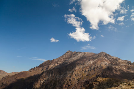 Landscape photography of steep mountains in summer, lonely clouds, and silent high altitude pastures, in the Aragonese Pyrenees, Huesca province, in the area of the Posets-Maladeta Natural Park.の写真素材