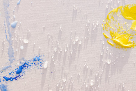 Blue, yellow and white oil and acrylic paint brushes on a blank canvas in the evening light....