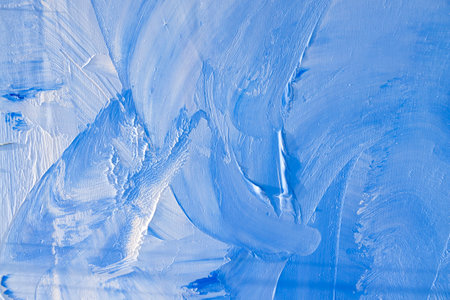 Blue and white oil and acrylic paint brushes on a canvas in the evening light. Artistic expression and painting exercises outdoors, away from home.の写真素材