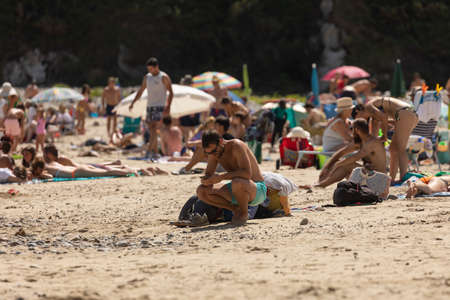 San Pedro de la Ribera, Spain - August 16, 2020: Beach in Asturias, full of bathers, umbrellas, tourists and local inhabitants on a summer day, enjoying the sand, the sea and the natural environment.のeditorial素材