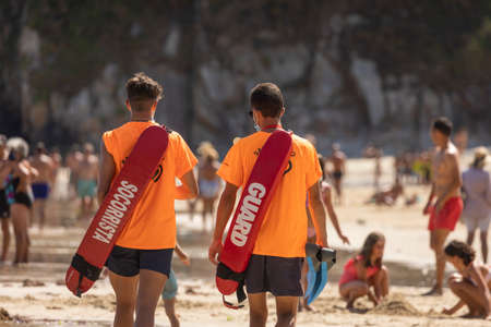 San Pedro de la Ribera, Spain - August 16, 2020: A couple of lifeguards from the public security services walk with the protective face mask on a beach in Asturias, in the middle of summer.のeditorial素材