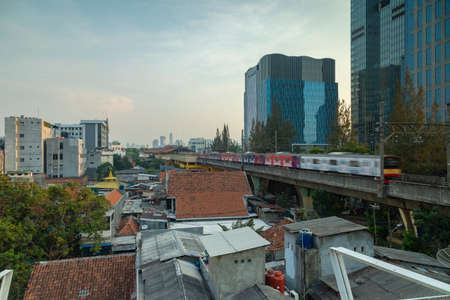 Jakarta, Indonesia - Oct 19, 2019: A train from the public transport of Jakarta, speeds down the tracks to the Gondangdia train stationのeditorial素材
