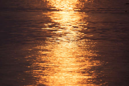 Orange and a bit purple sunset sunlight, reflected on the uneven surface of the water, on the island of Koh Chang, Gulf of Thailandの写真素材