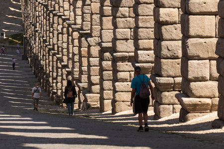 Segovia, Spain - June 2, 2021: Detail of the huge granite columns of the Aqueduct of Segovia, and some people, from Teodosio el Grande streetのeditorial素材