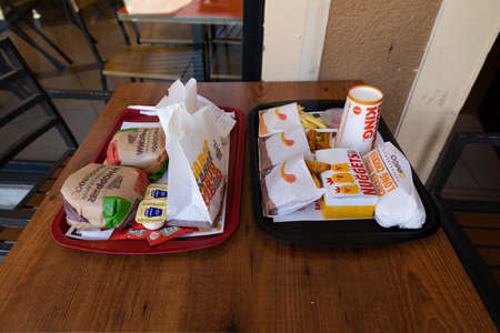 Segovia, Spain - June 2, 2021: A couple of fast food trays, with hamburgers, chicken, fries and soft...