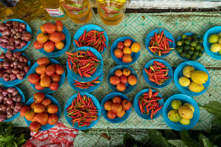 Waisai, Indonesia - Oct 17, 2019: Plates with tomatoes, garlic, peppers and other products, local market stall in Waisai, Raja Ampatのeditorial素材