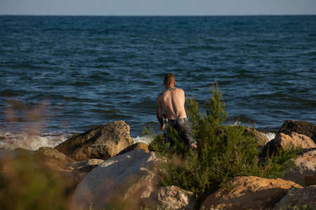 Torreblanca, Spain - July 16, 2020: A young man throws the rod trying to fish something for dinner, in the Prat de Cabanes Natural Parkのeditorial素材