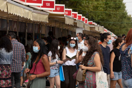 Madrid, Spain - Sep 11, 2021: A woman looks at a book, just bought, among the crowd of people, at the 80th Madrid book fairのeditorial素材