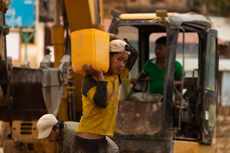 Indein Village, Myanmar - Jan 05, 2020: Portrait of a young man working on a construction site, carries sand in a bucket, Shan Stateのeditorial素材