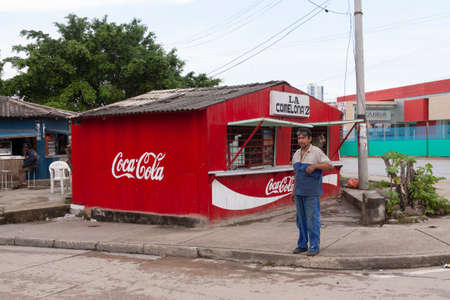 Cartagena de Indias, Colombia-Nov 21, 2010: A man, a worker in a car workshop, watches me while he smokes on his rest shift in front of a food stallのeditorial素材