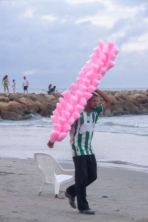 Cartagena de Indias, Colombia - Nov 21, 2010: A street vendor of pink cotton candy walks in search of customers on the Bocagrande beachのeditorial素材