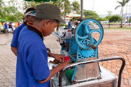 Cartagena de Indias, Colombia - Nov 21, 2010: A young boy works preparing ice creams, flavored ice slushies and soft drinks at a street stall in the Plaza de Los Zapatos Viejosのeditorial素材