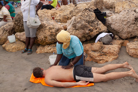 Cartagena de Indias, Colombia - Nov 21, 2010: A woman gives a massage to a tourist, lying face down on the beach of Bocagrandeのeditorial素材