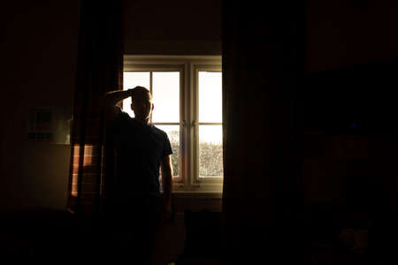 A man, middle-aged, adult, waits for the results of a covid-19 pcr test, self isolate, in a hotel room near Manchester airport, UKの写真素材