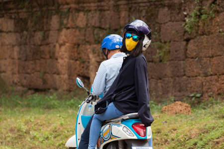 Angkor, Cambodia - Nov 24, 2019: A tourist travels on a motorcycle with her driver, along one of the roads that run through Angkor Wat, in the Angkor Archaeological Park, near Siem Reapのeditorial素材