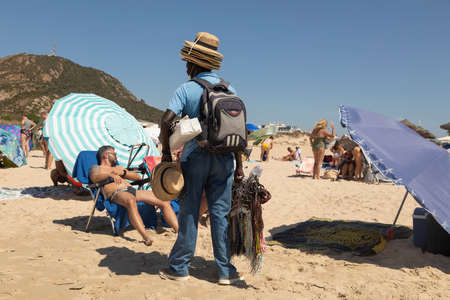 Zahara de los Atunes, Spain - Sept 04, 2021: A man, an immigrant, from Africa, works hard as a street vendor, on the beach, Cadiz provinceのeditorial素材