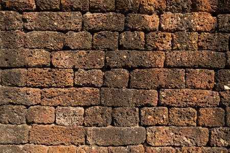 Textured background of a wall of irregular stones of reddish ochre colors, in one of the temples of Sukhothai Historical Parkの写真素材