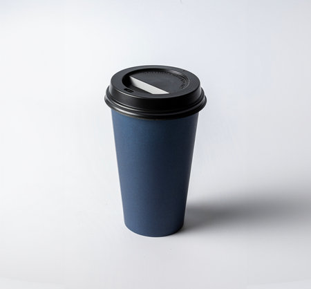 Mockup of a large size empty blue cardboard cup, with black cap, on a white background, typical for coffee or infusionsの写真素材