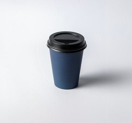 Mockup of a medium size empty blue cardboard cup, with black cap, on a white background, typical for coffee or infusionsの写真素材