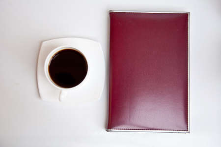 brown notebook and black coffee on white backgroundの写真素材