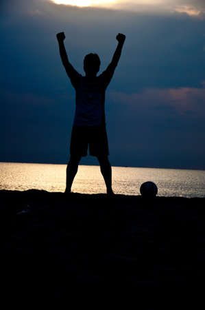 silhouette of man playing soccer on the beachの写真素材