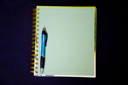 green notebook and pen on black backgroundの写真素材